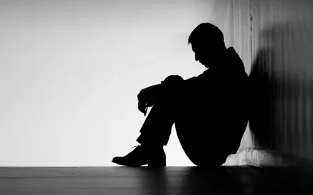 Мужчина сидит на полу в темном коридоре